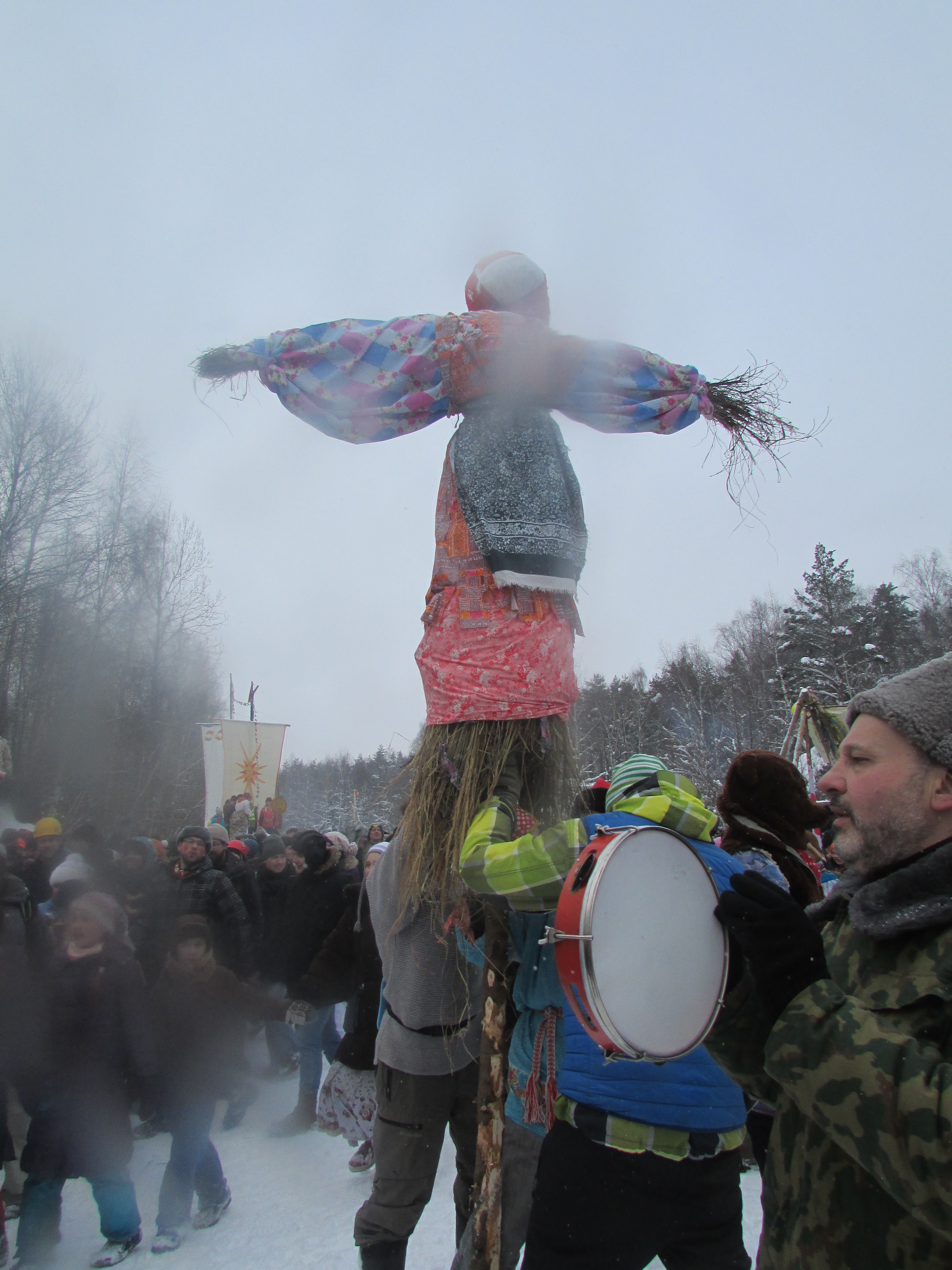 Straw effigy of a woman in traditional dress surrounded by a crowd