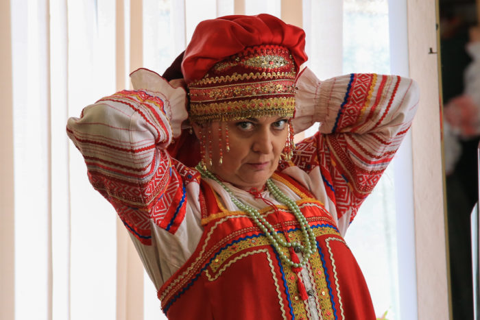 woman in Russian folk dress adjusts her headgear